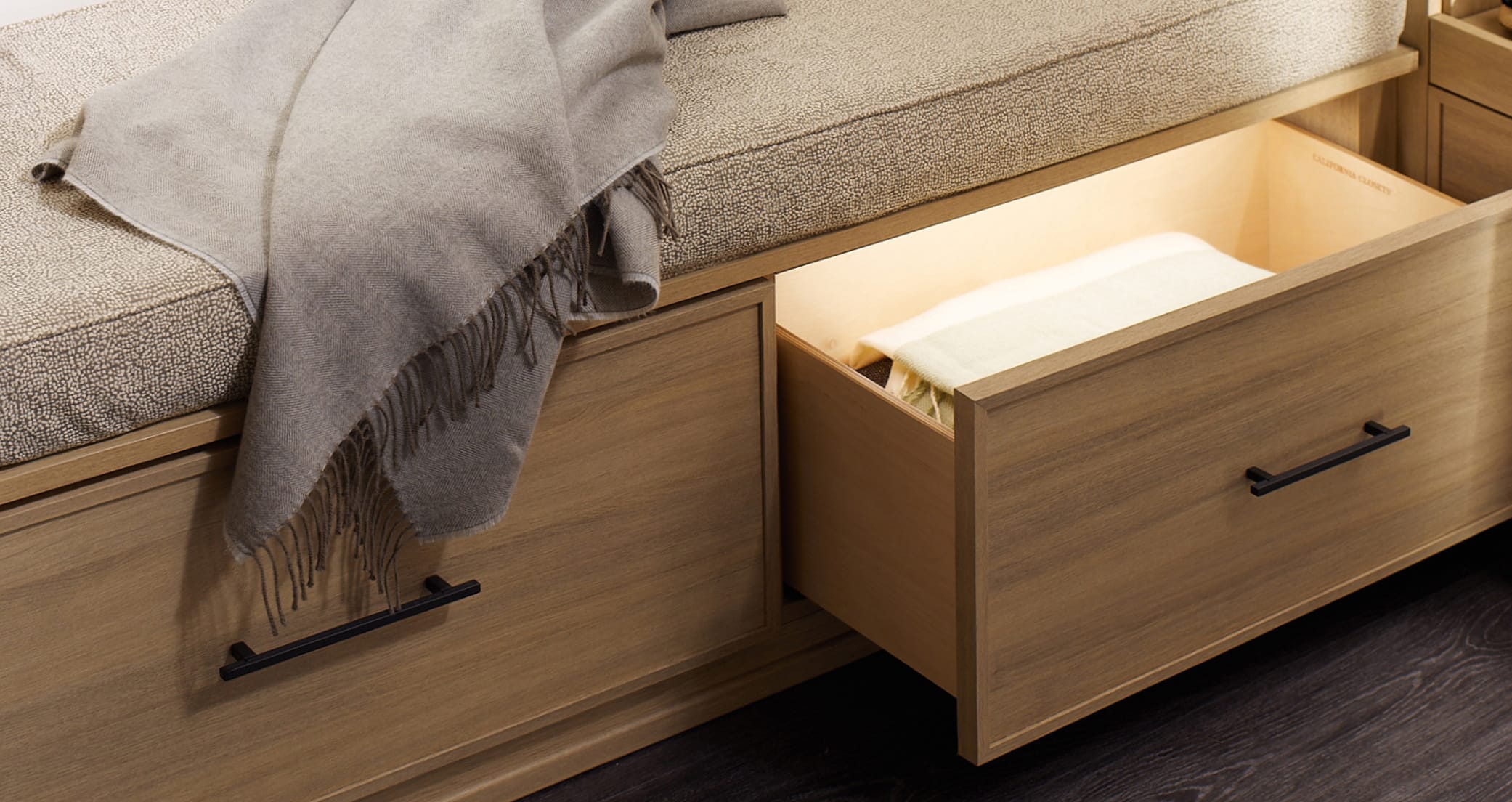 Custom drawers in natural wood grain finish with internal led lighting by California Closets