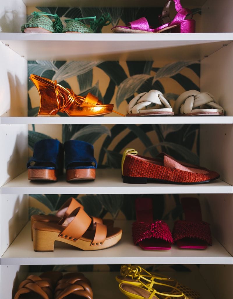 Shoe storage designed for Justina Blakeney's walk in closet with colorful wallpaper by California Closets